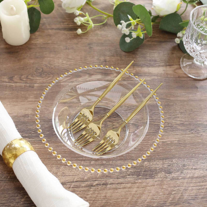 Elegant clear plate with gold forks, set on a rustic wooden table.