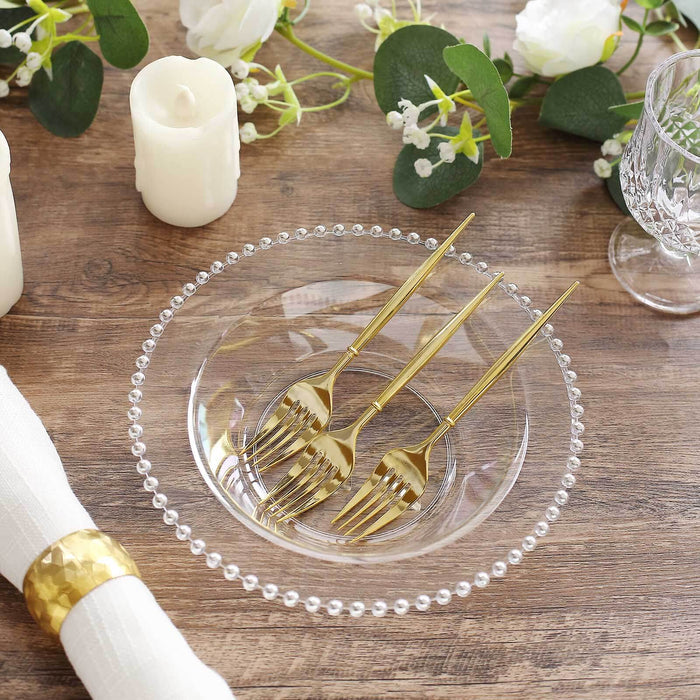 Elegant clear bowl with gold forks, surrounded by floral decor and candles.