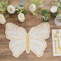 Gold glitter butterfly placemat on a wooden table with flowers and candles.