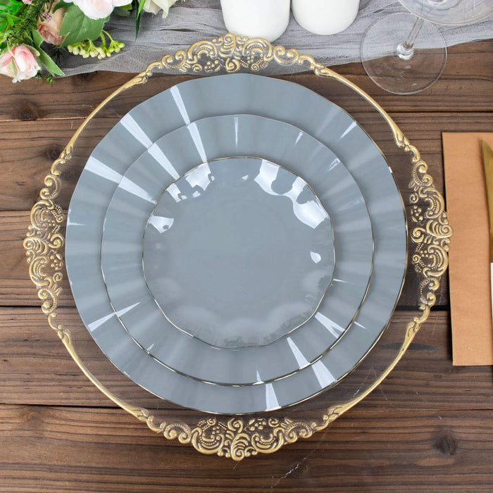 Elegant gray plates with ornate gold trim stacked on a wooden table.