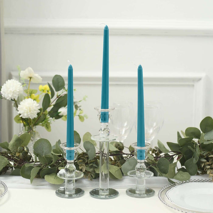 Teal taper candles in glass holders with greenery and flowers