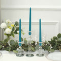 Teal taper candles in glass holders with greenery and flowers