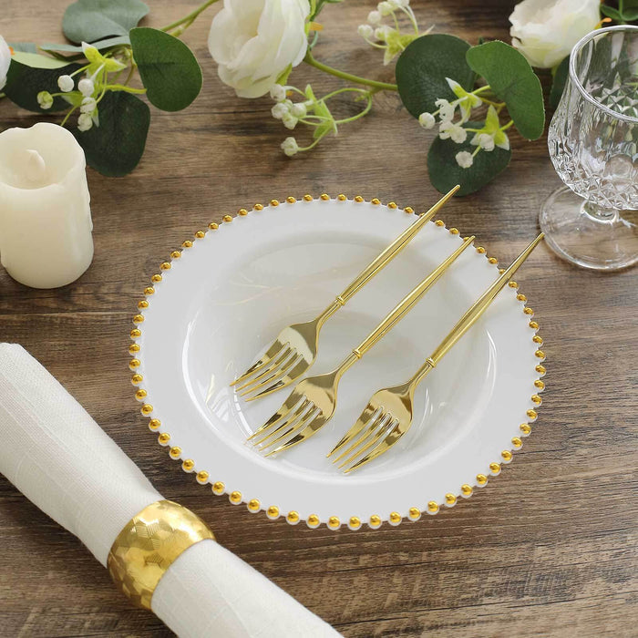 Elegant white plate with gold beaded rim and three gold forks, styled with floral accents.
