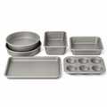 Six-piece bakeware set with two round pans, loaf pan, square pan, baking sheet and six-cup muffin pan on white.